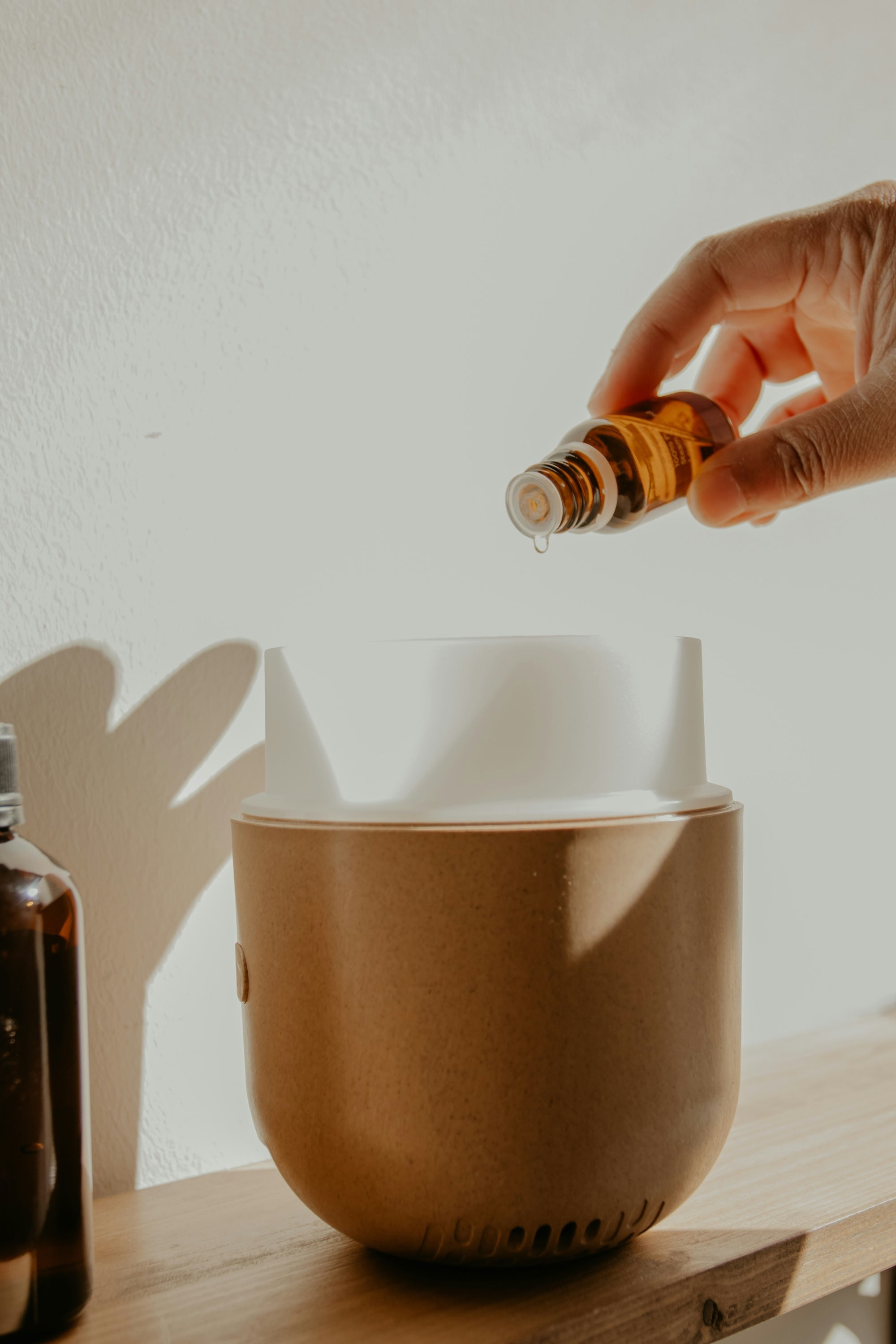 A person is adding essential oils to an aromatherapy diffuser drop by drop, highlighting all of the pure essential oils offered through The Good Planet Company.
